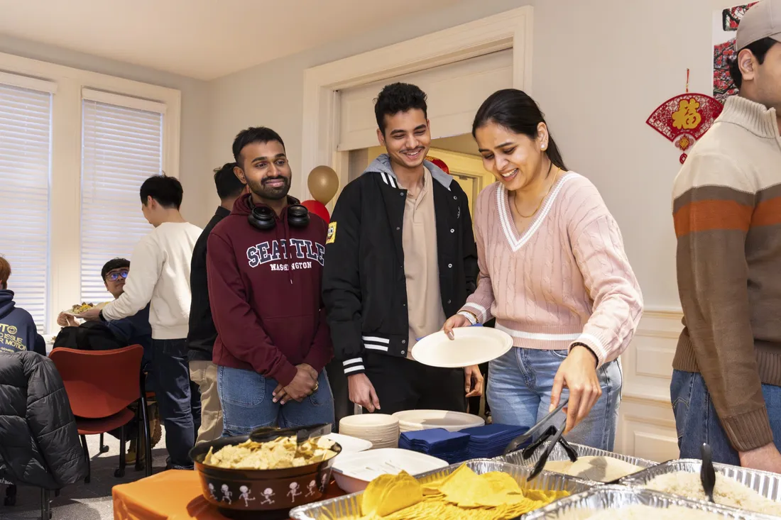 International students grabbing food and chatting at a campus-coordinated social event.