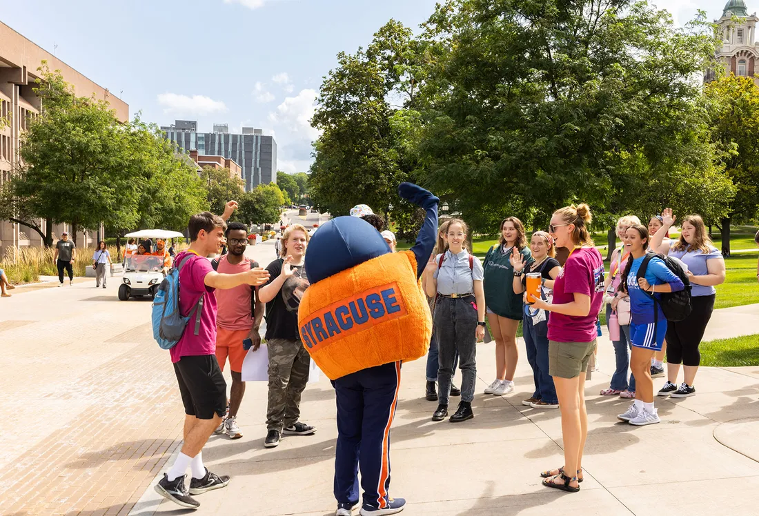 Otto and students interact on campus on a sunny summer day.