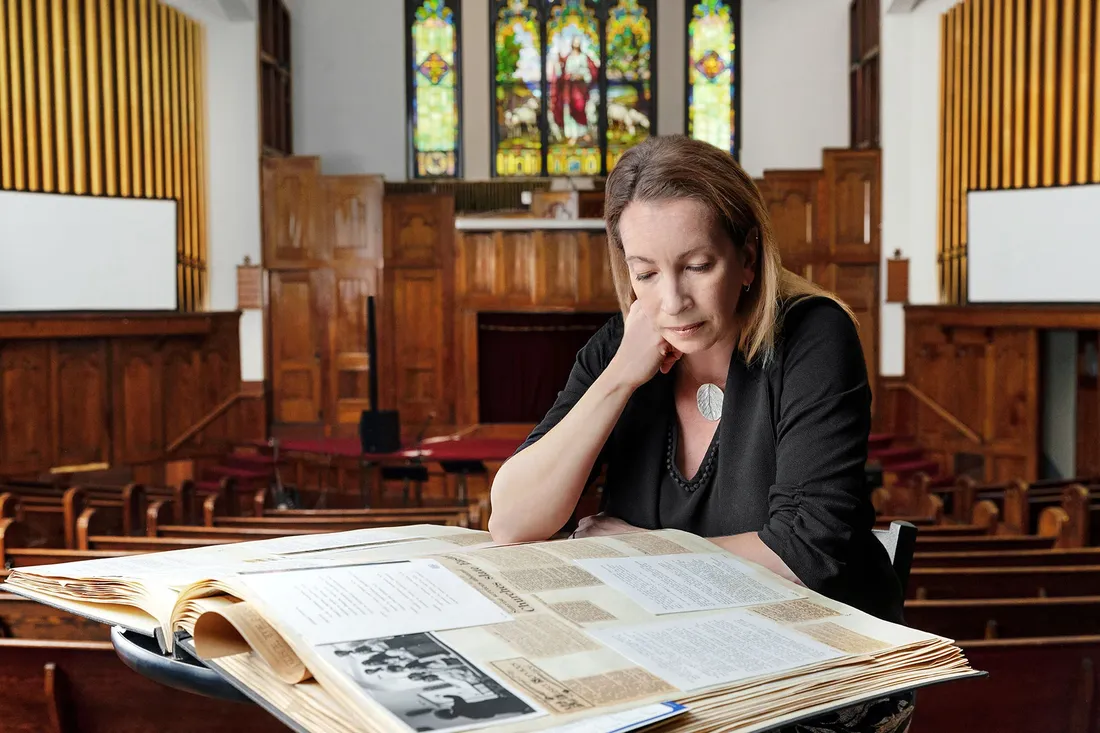 Emily Stokes looks at archival book of newspaper clippings.