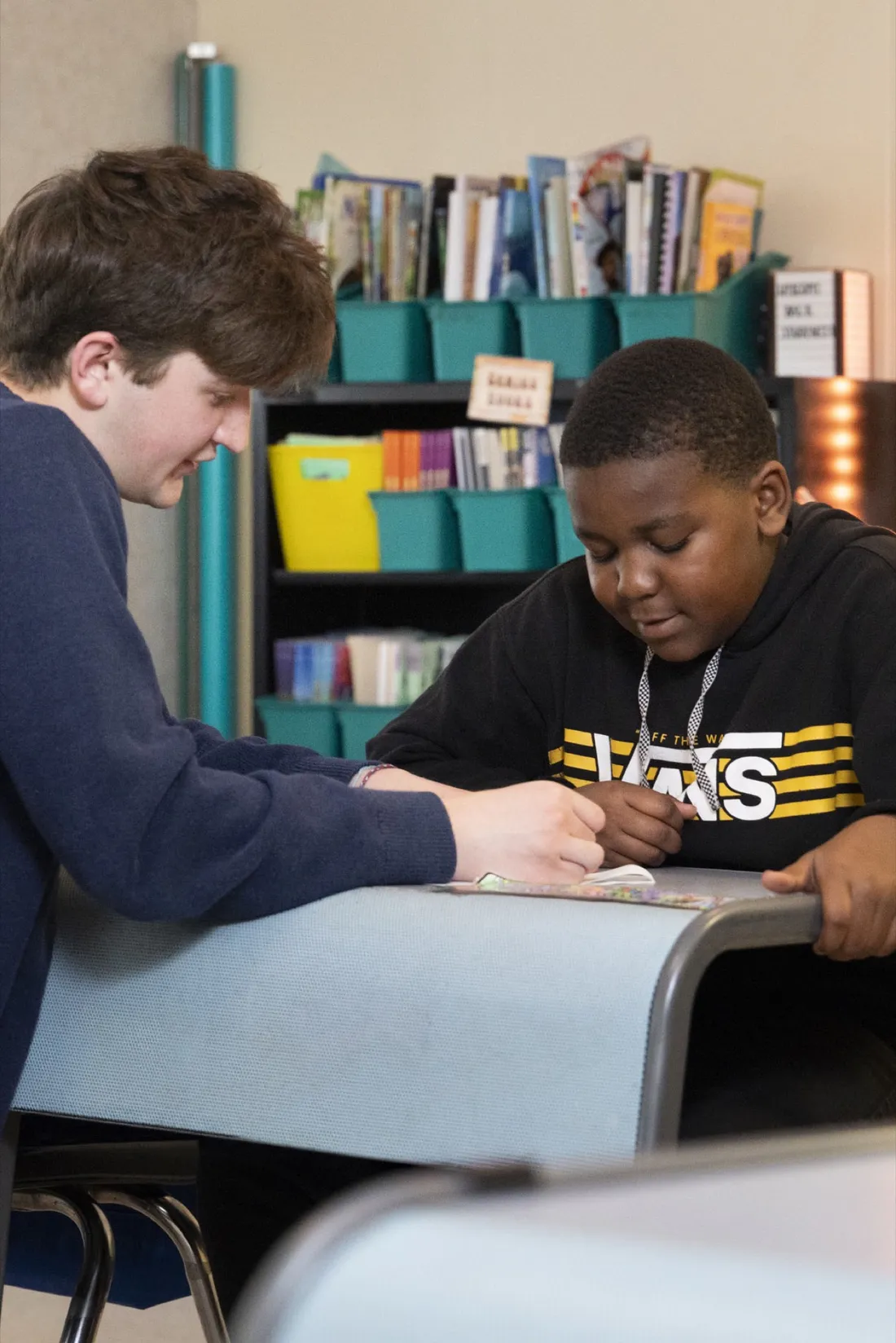 Will Baker '27 sitting and helping an elementary school student with their work.