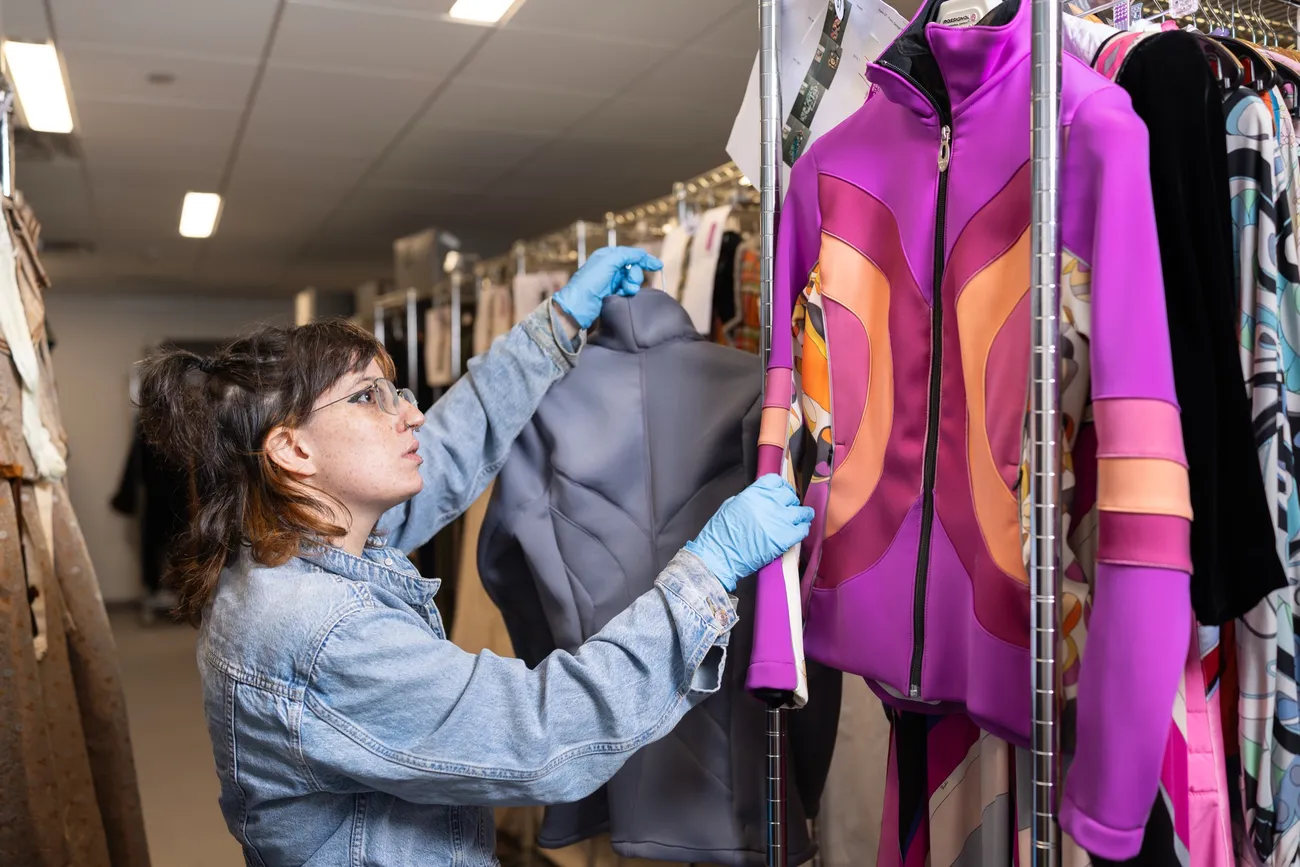 Student examining different articles of clothing in the Sue Ann Genet Costume Collection.