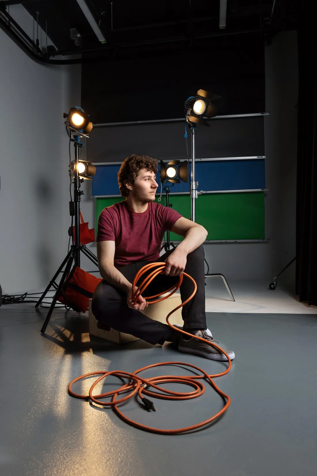 Jeremy Shinder sitting on floor holding extension cord.