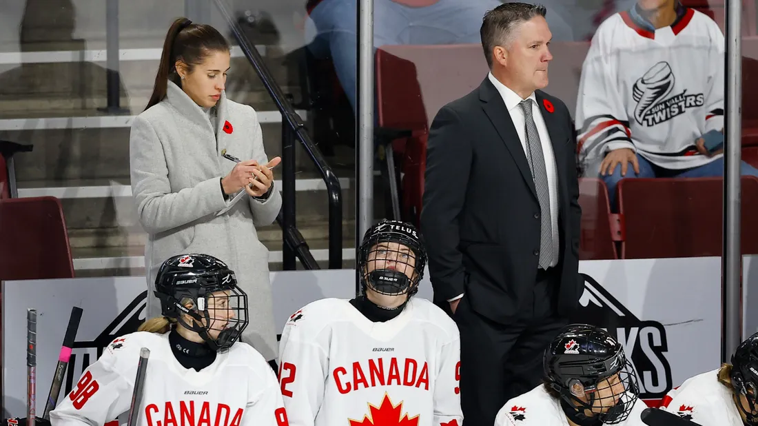 Three of Team Canada's women's ice hockey players and their coach, SU hockey coach Britni Smith, sitting on the sidelines of an ice rink.