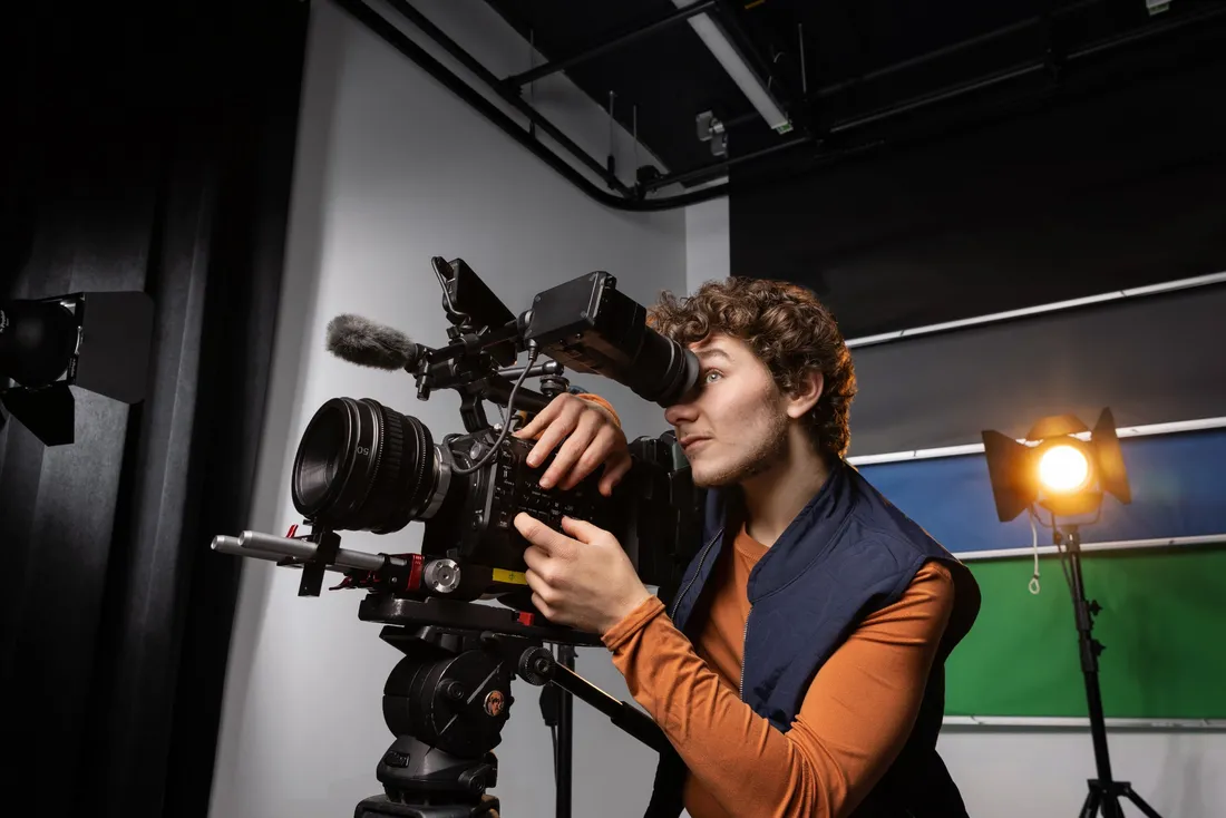 Man looks through lens of video camera.