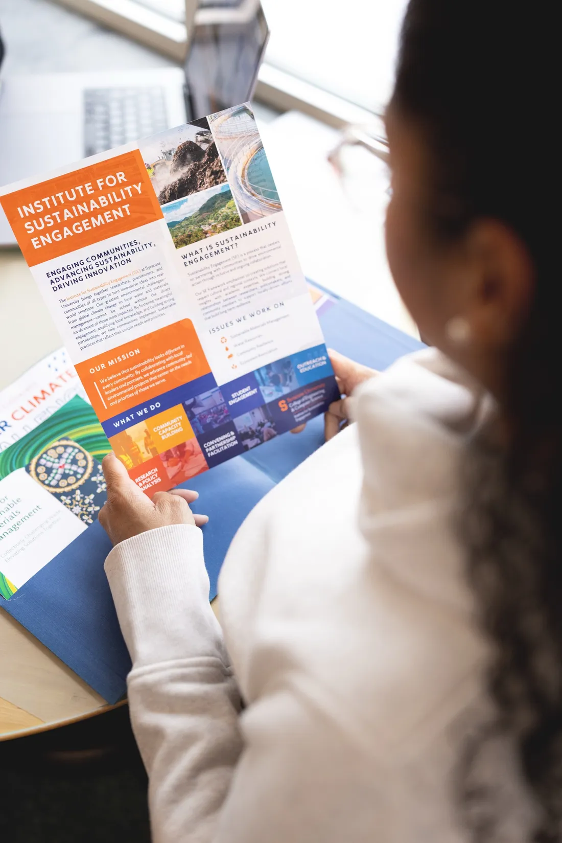 Woman holding a pamphlet outlining Syracuse University's Institute for Sustainability Engagement.
