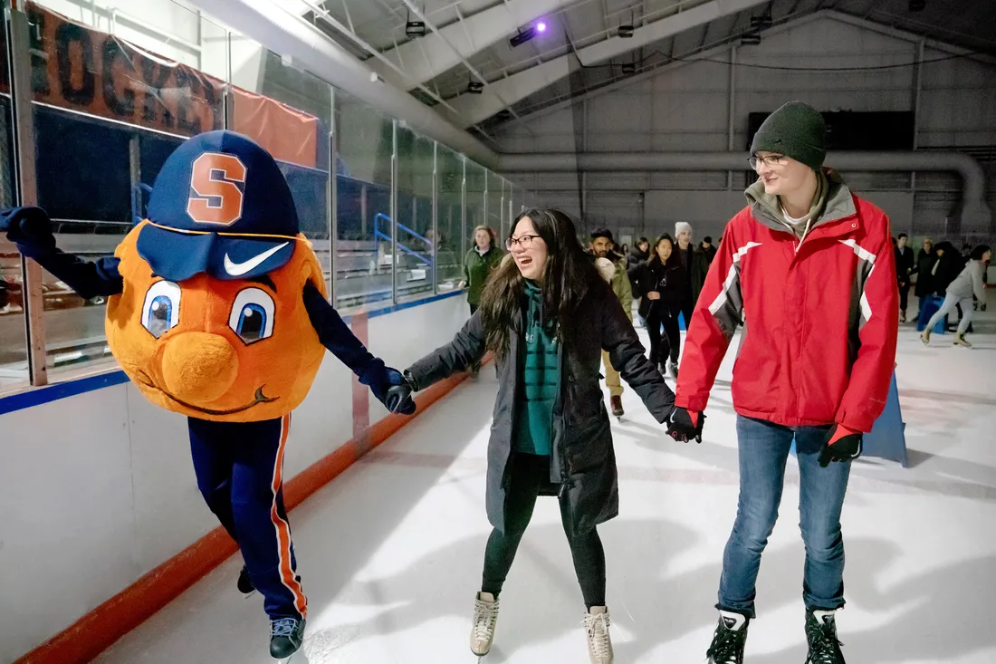 Photo of Otto ice skating with two students, all holding hands.