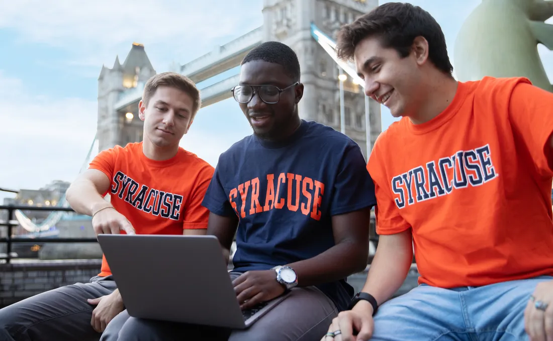 Students looking at laptop next to Tower of London