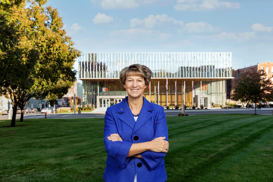 Portrait of Eileen Collins standing on a mowed law, a view of the National Veterans Resource Building behind her.