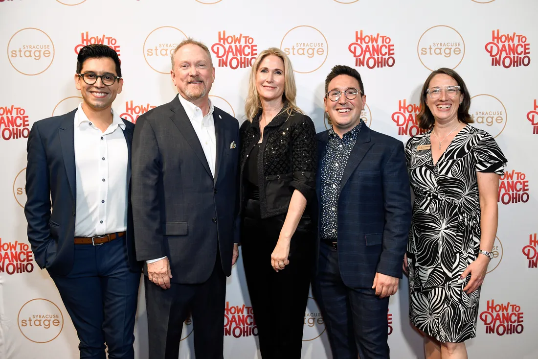 Group photo of smiling directors and alumni in front of a backdrop that says "Syracuse Stage, How to Dance in Ohio."