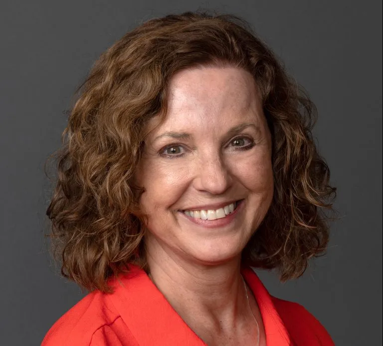 Joanne Reid smiling in an orange shirt.