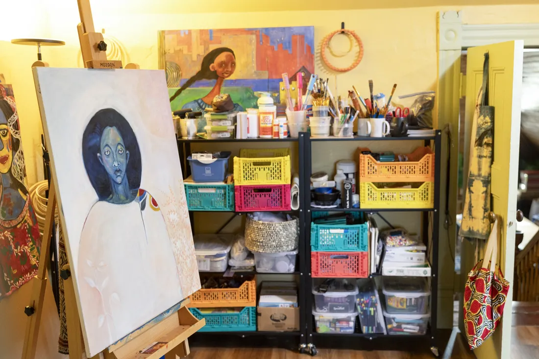 A painting hanging on an easel inside of an art studio.