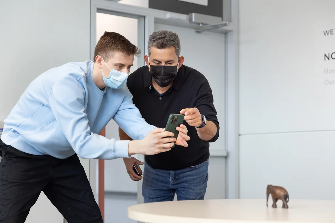 Professor Dan Pacheco directing a student next to him to scan a small elephant object on the table.