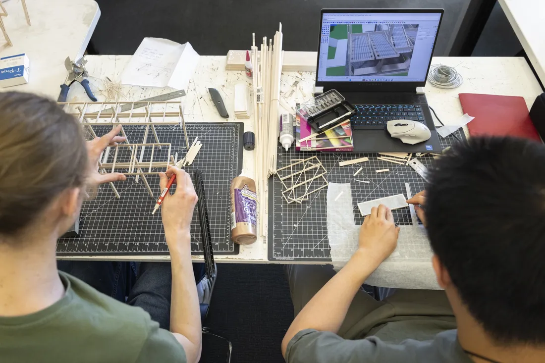Two students building wooden scale models in a classroom.