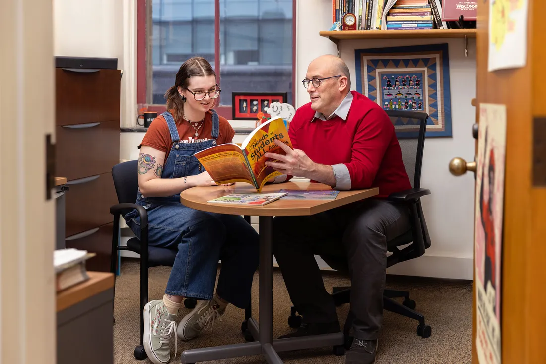 Professor and student studying at table.