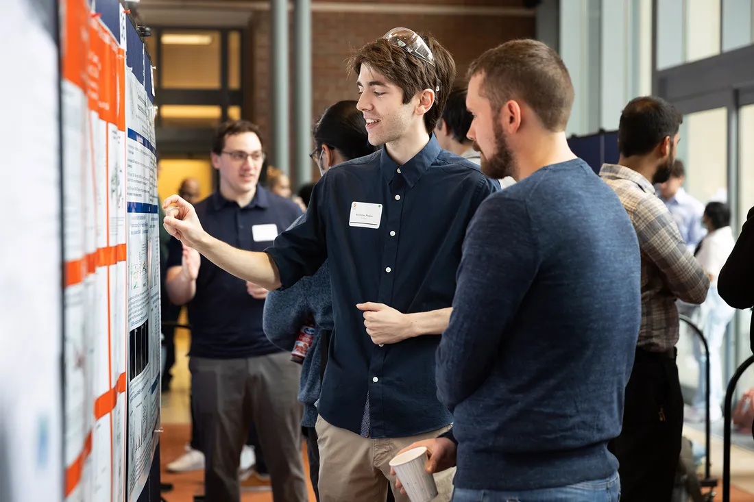 Medium shot of Nicholas Najjar pointing at his poster.