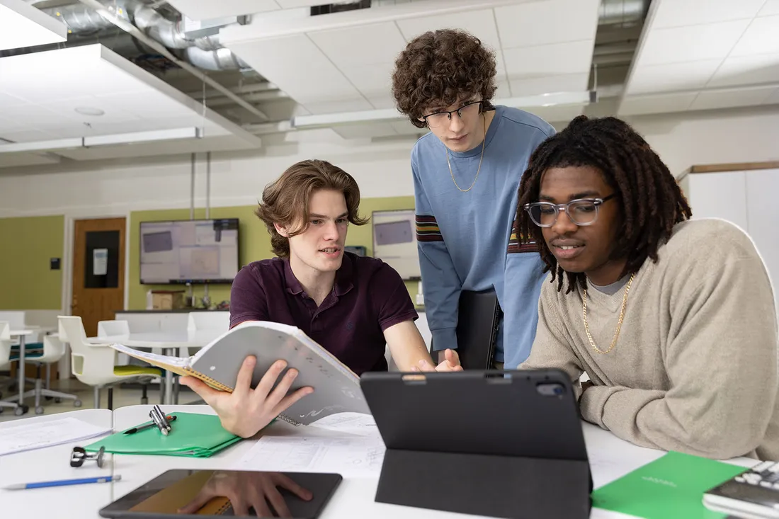 Three students looking at computer together.