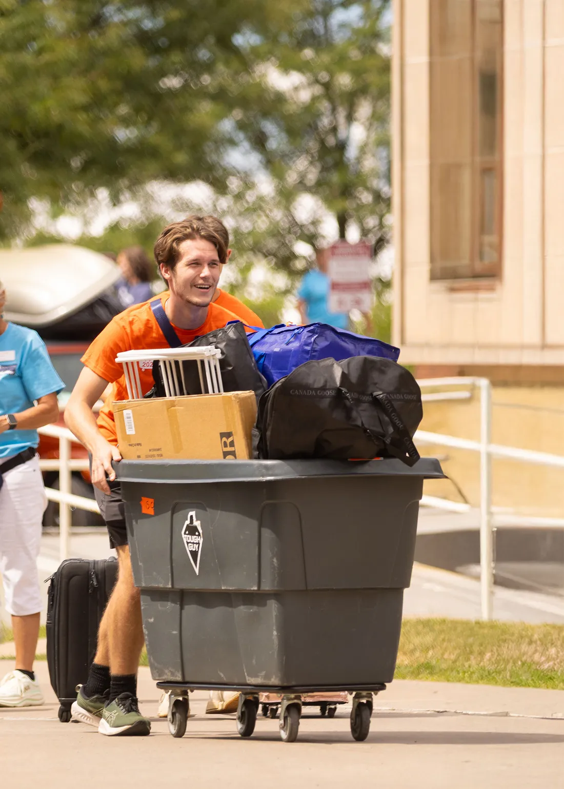 Goon squad student pushing a bin to help students move in.