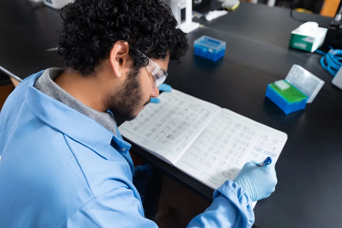 Student taking notes in a chem lab.