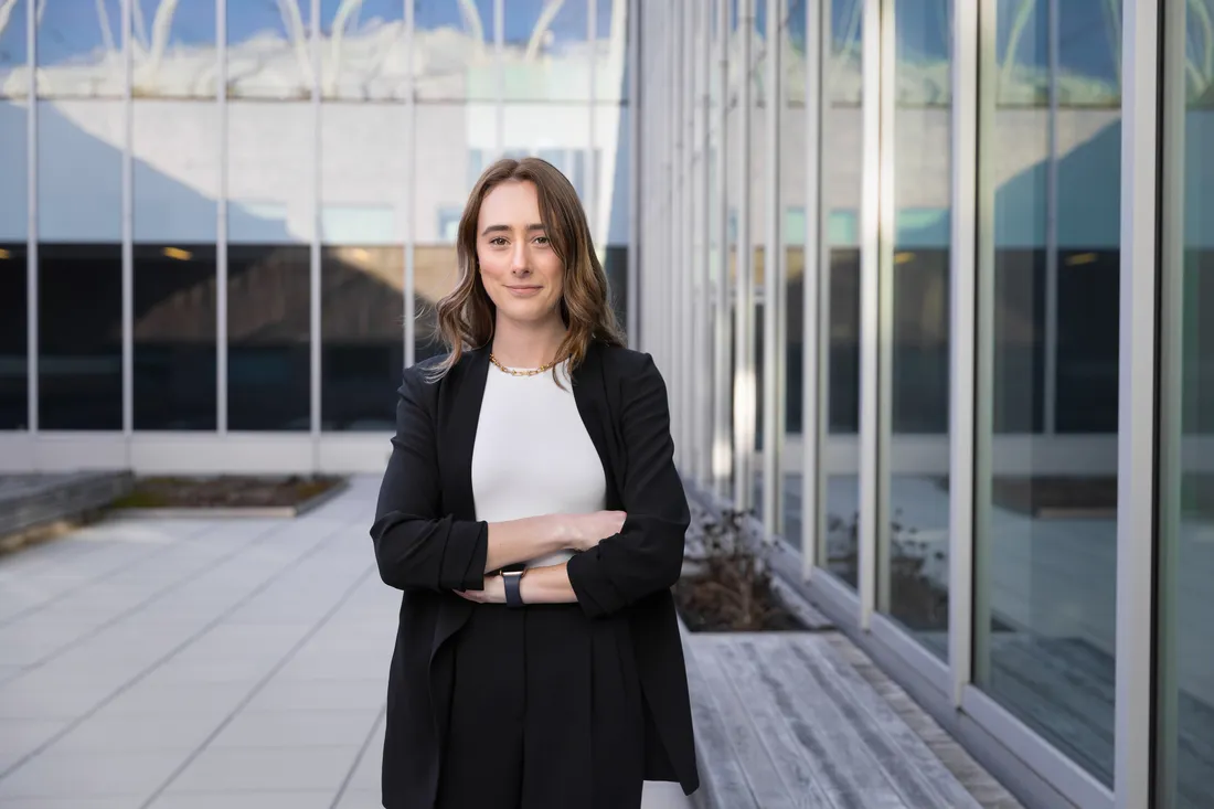 Cecily Capo smiling with her arms crossed and standing outside the College of Law.