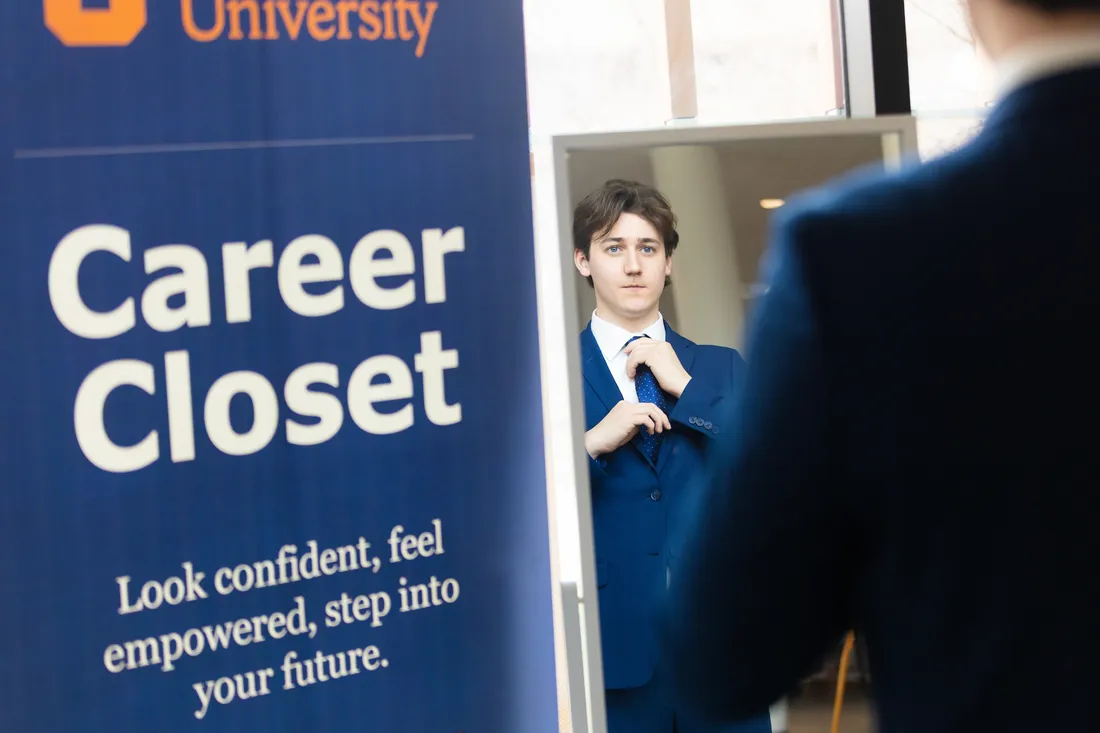 A student getting dressed using the Syracuse University career closet.