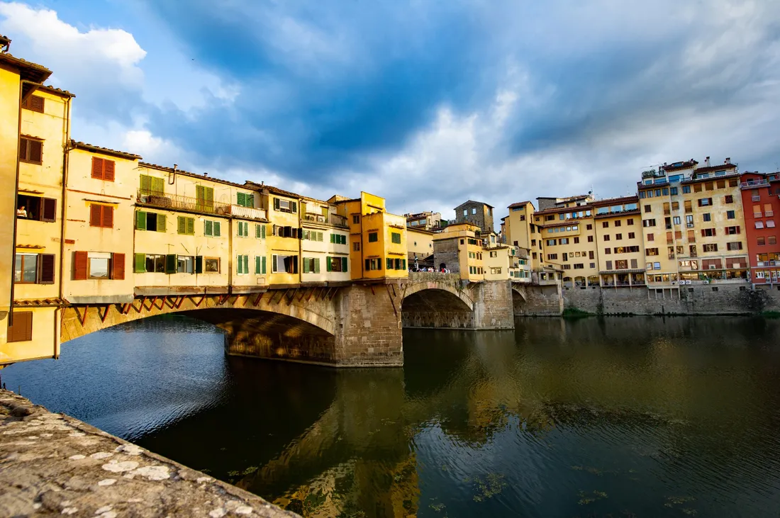 View of bridge and buildings across a river in Florence, Italy.