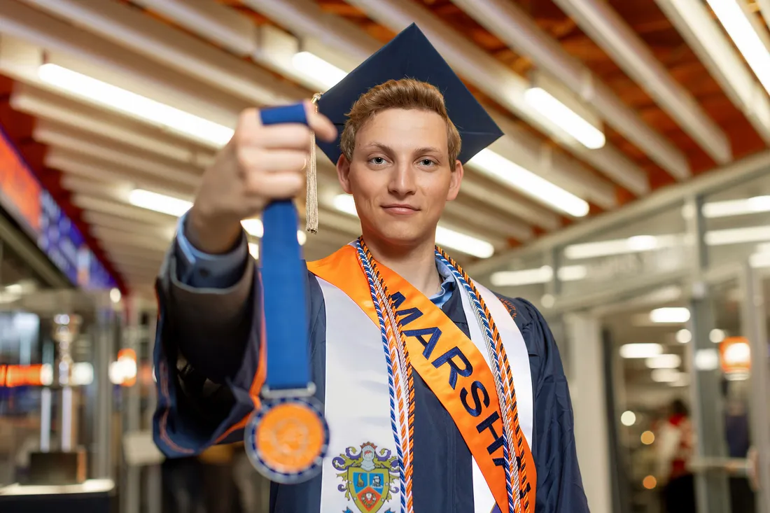 Evan Kalish holding his medal while staring at the camera.