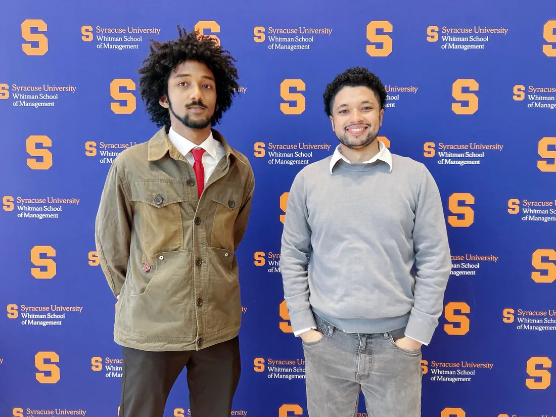 Kristian Nunez and Jon Carter standing in front of a wall inside of the Martin J. Whitman School of Management.
