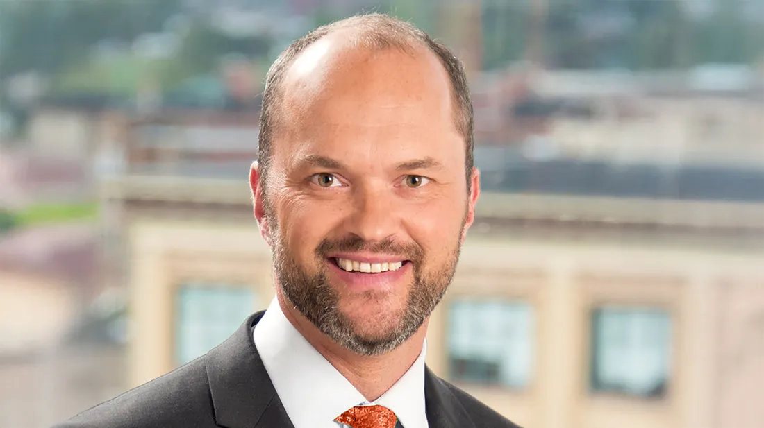Gabriel Nugent smiling in a suit with an orange tie.