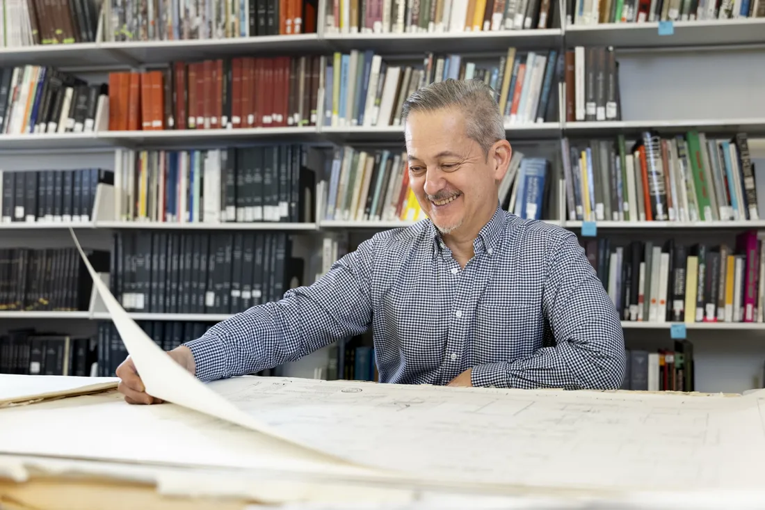 Professor Lawrence Chua looking at architectural maps and smiling.