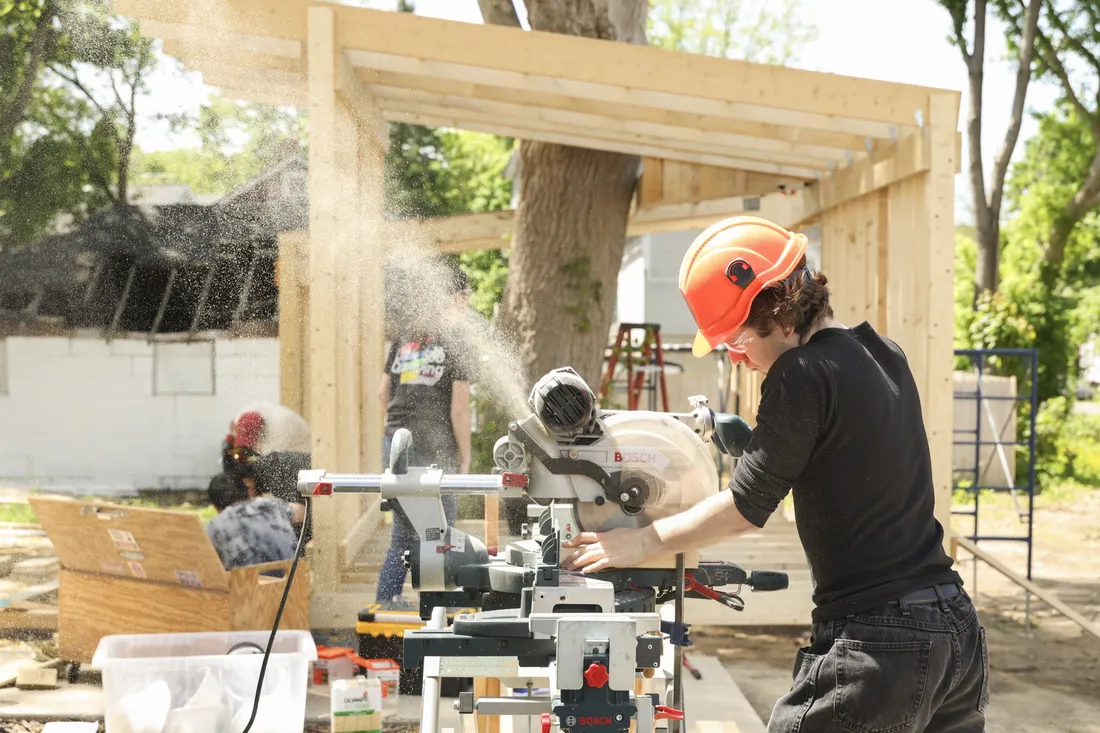 Student using a table saw to cut a piece a wooden board.