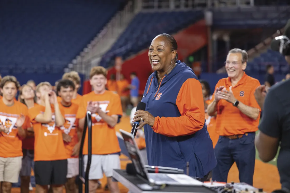 Person standing at microphone and speaking to cheering crowd.