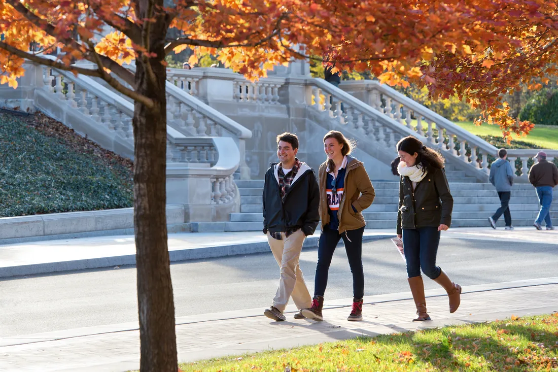 Students walk on Einhorn Walkway on autumn day.