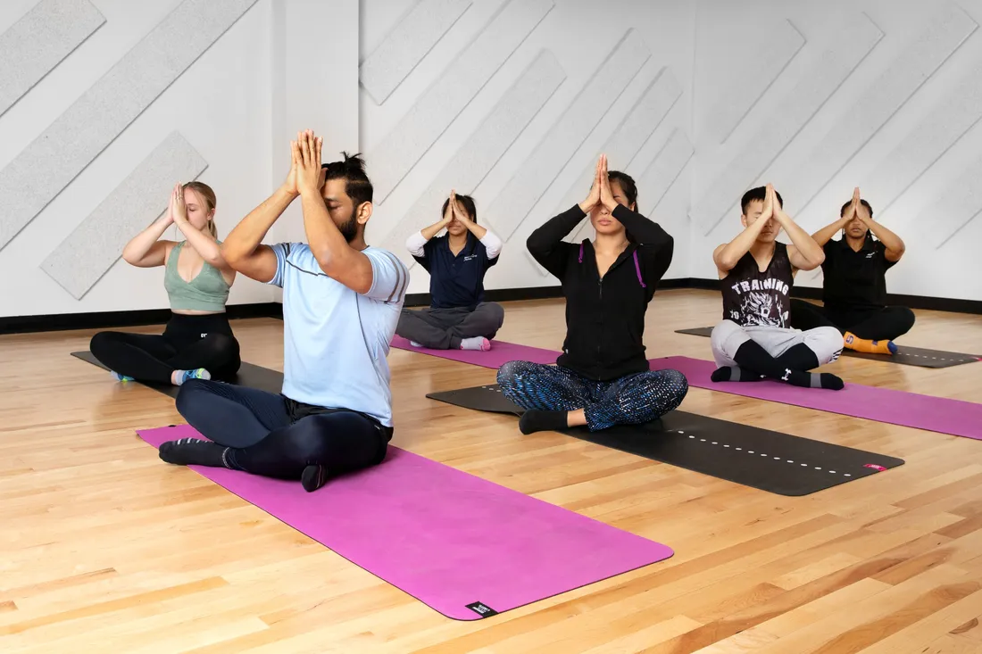 Group of six people in yoga poses in a room with wood floor.