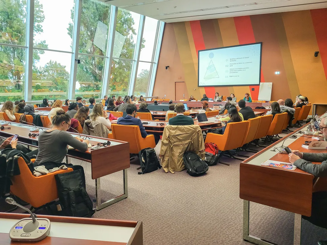 A group of people in a conference room at the world forum on democracy.