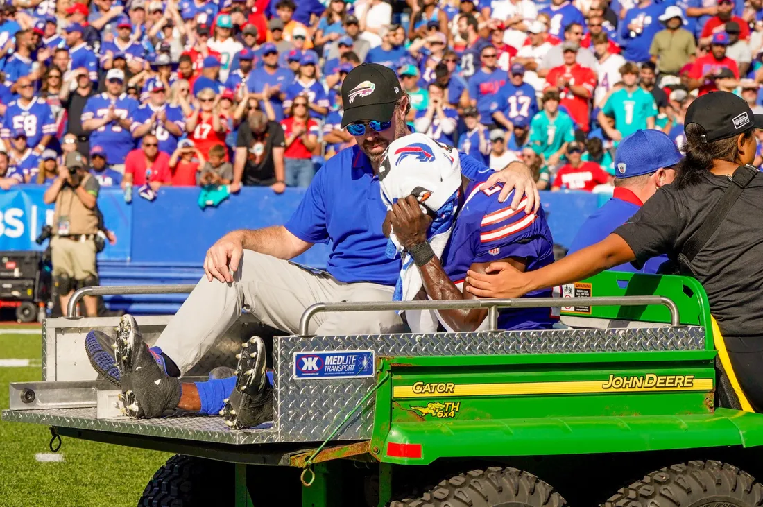 Marc Fineberg sitting on the back of a cart with an injured Buffalo Bills player.