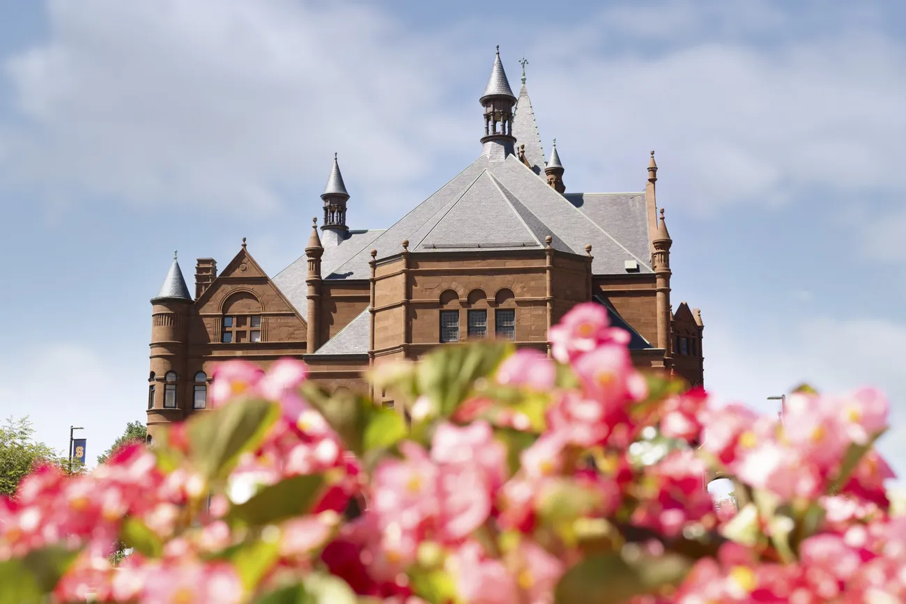 The top of the tower at Crouse College with pink flowers in the foreground.