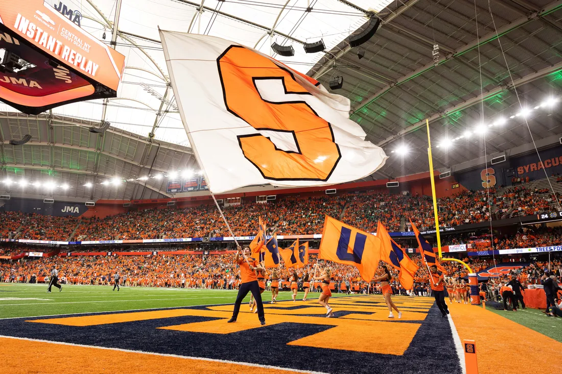 Student waving a Syracuse University flag during a game in the JMA Wireless Dome.