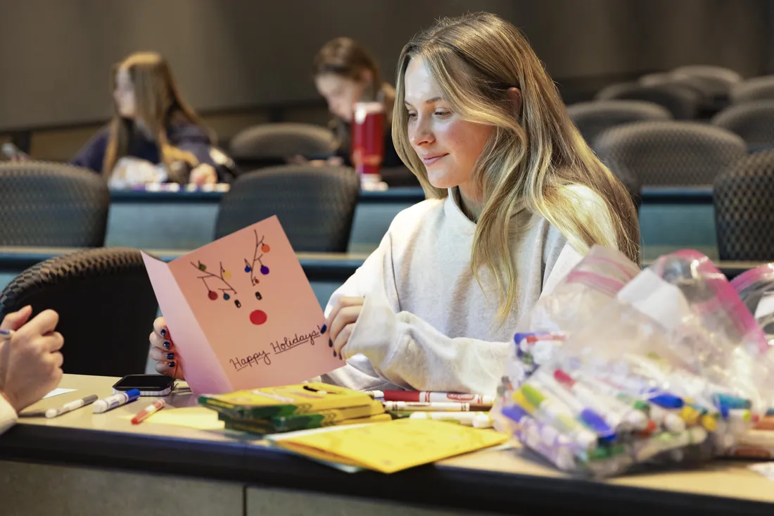 Student reading holiday card they've written for Letters of Love's annual letter writing campaign.
