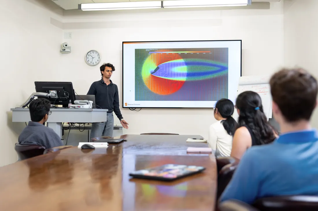 Emanuel Boutros '27 standing at the front of a classroom giving a presentation to an undergraduate research team.