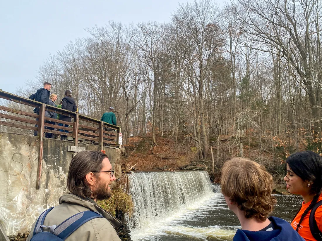 People standing outside in front of a river dam.