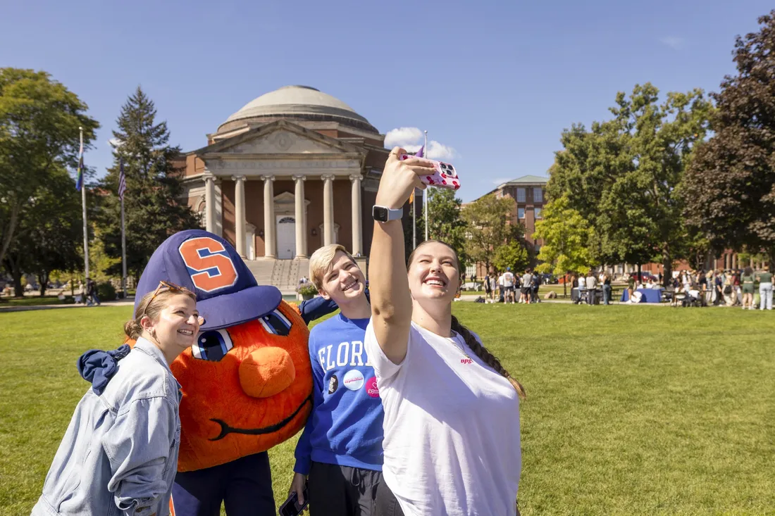 Students taking a selfie with Otto the Orange.