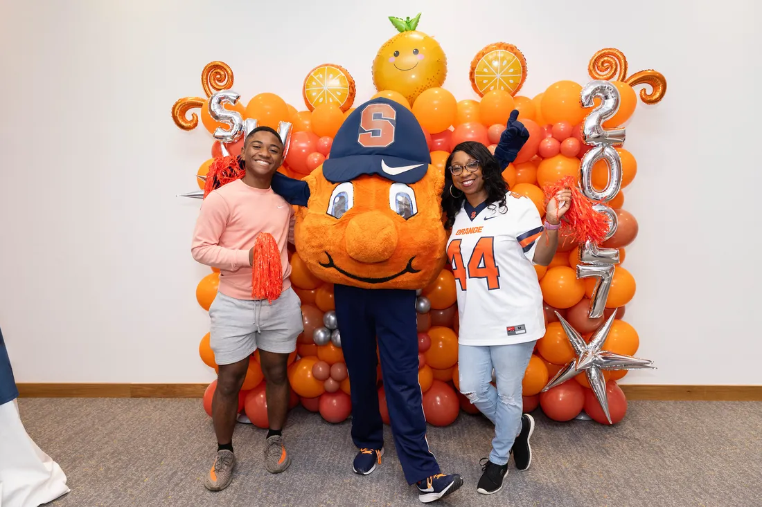 A family standing with Otto the orange.