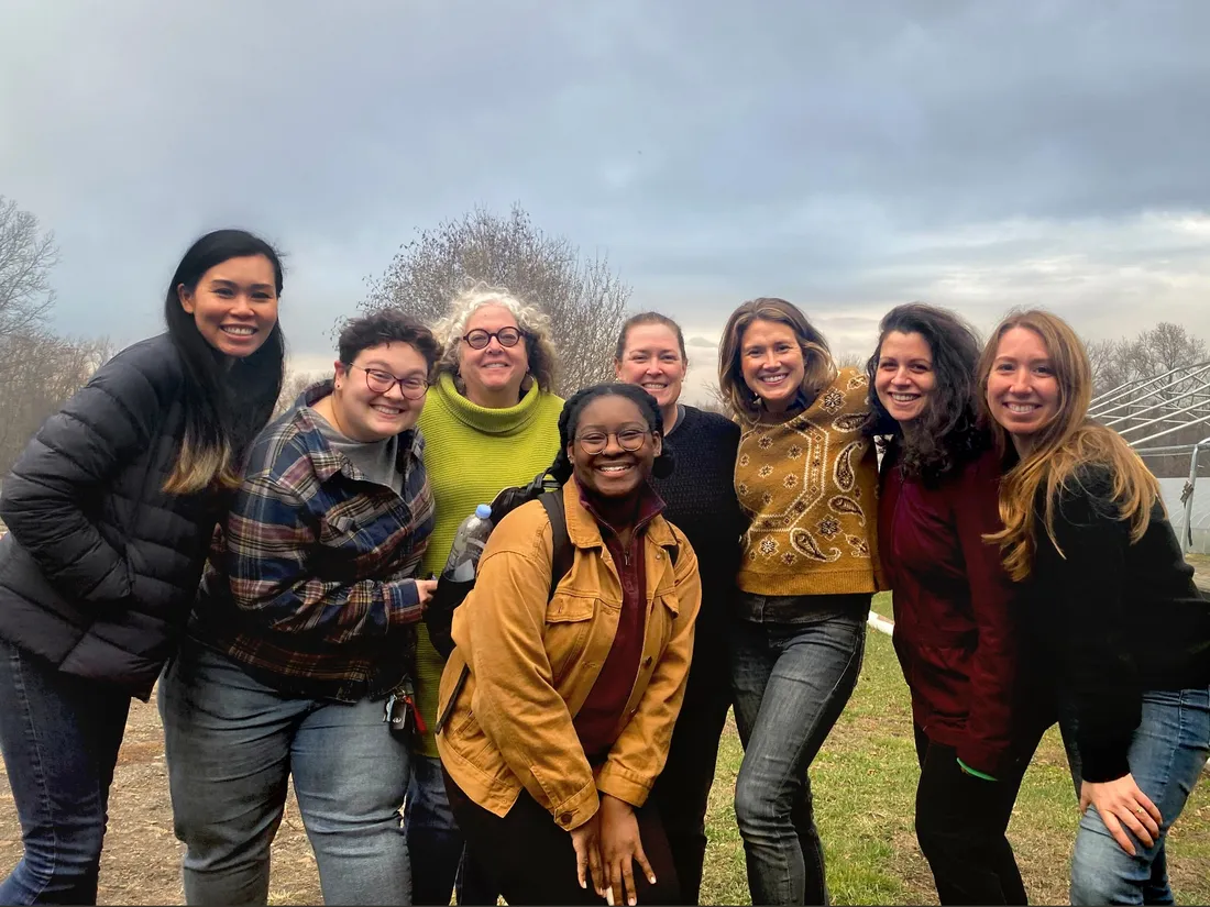 A group of people standing outside on an overcast day, smiling at the camera.