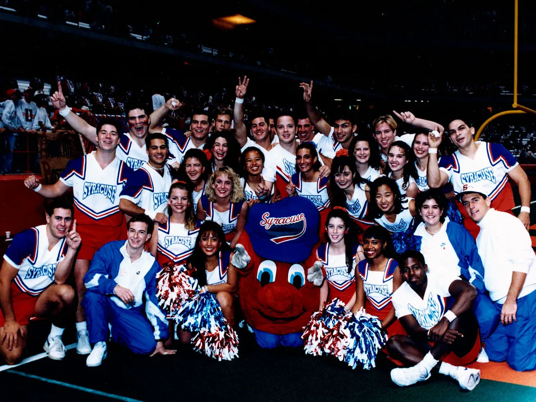 Vintage Otto the orange mascot standing with cheerleaders.