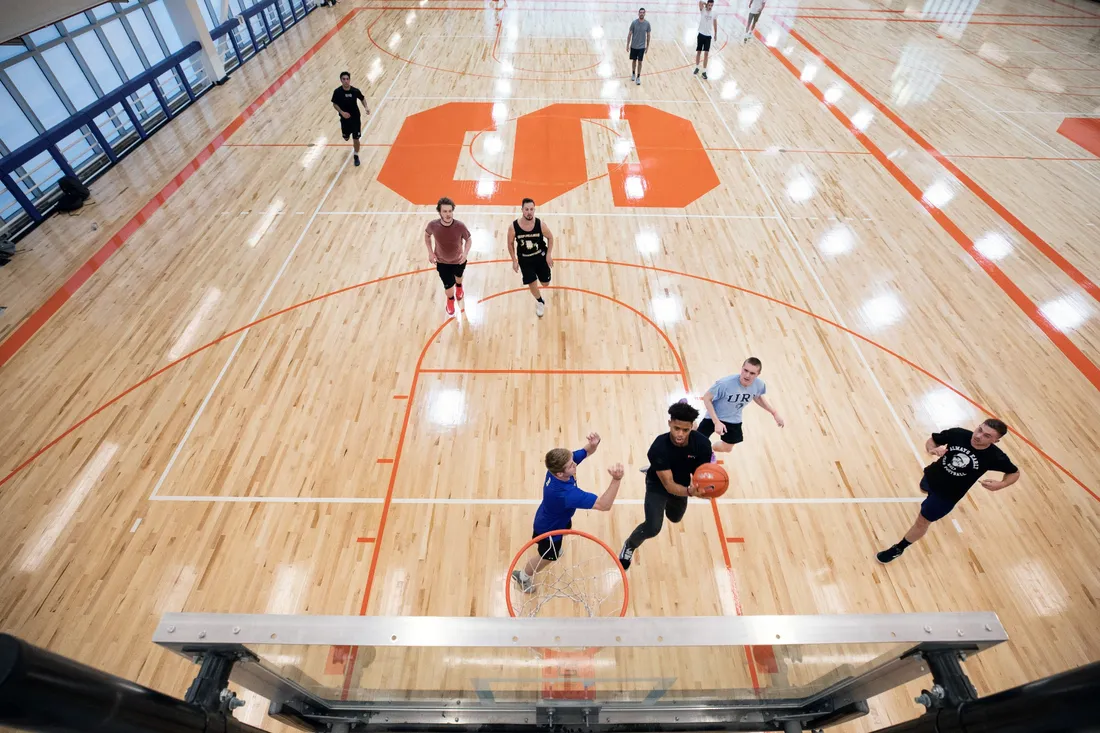 Overhead view of people playing basketball on interior court.