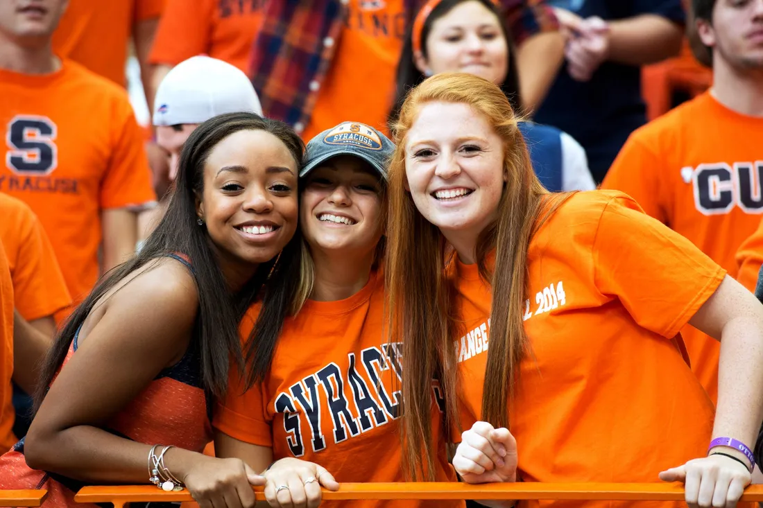 Portrait of three students smiling at game in the Dome.