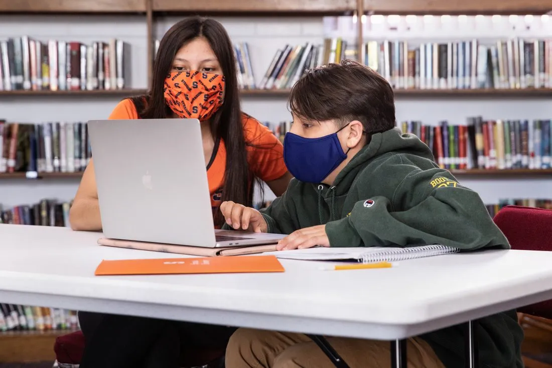 Logan booth and a student sit at a laptop in a classroom.