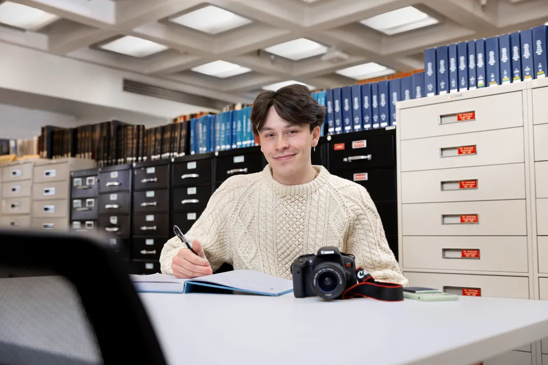 Ben Piers sitting at desk with camera.