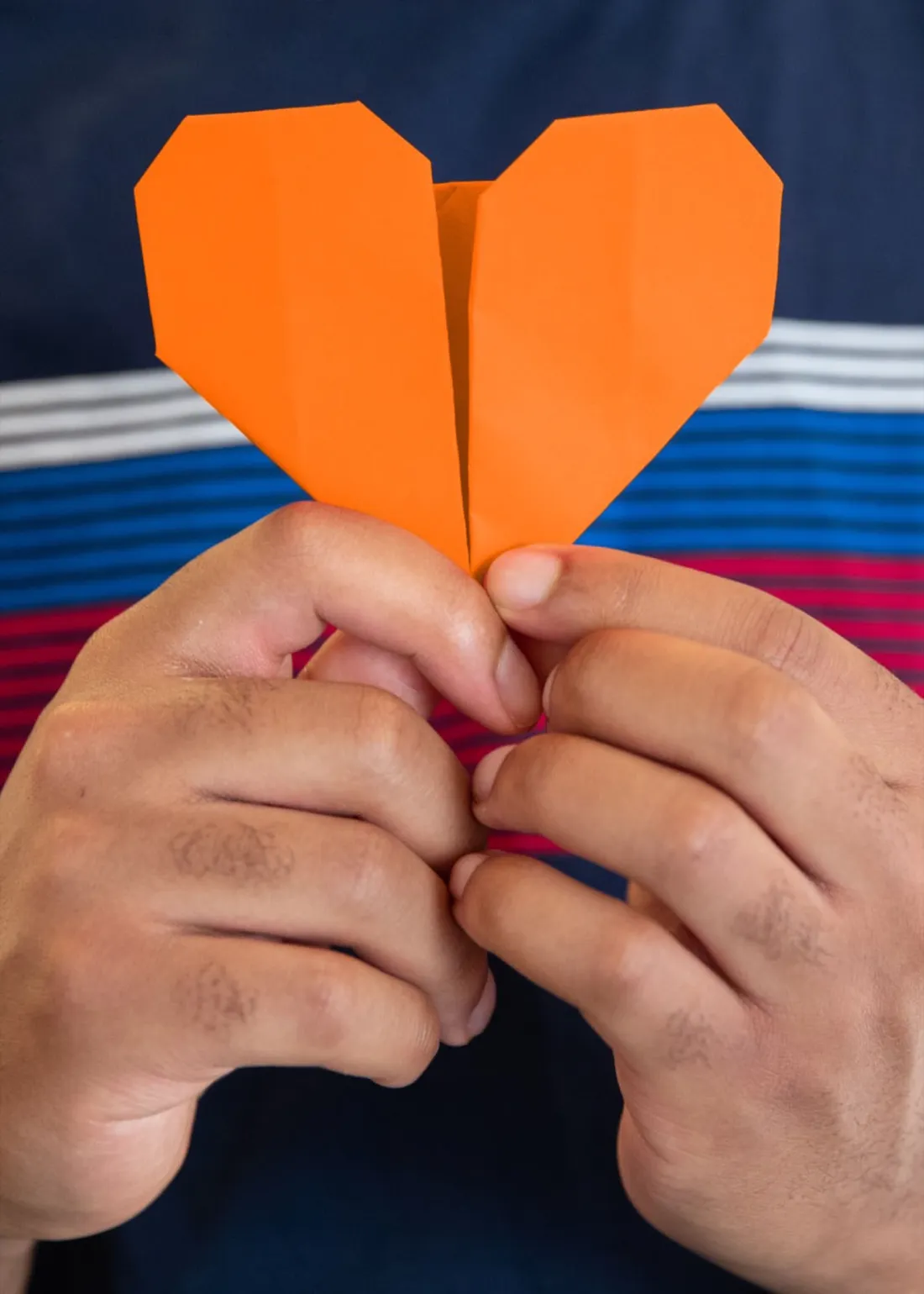 Student holding an orange origami heart.