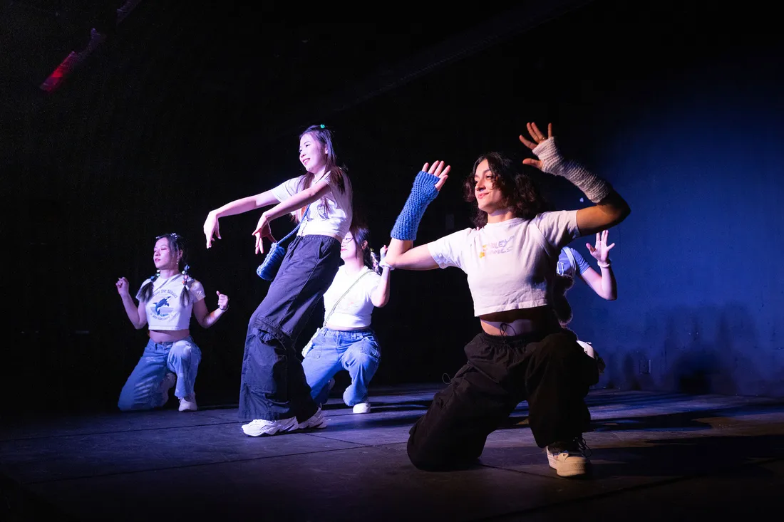 Students on stage in hip-hop costumes perform a dance.